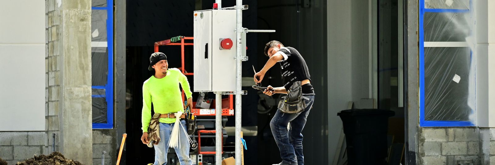 Two technicians installing an electrical panel on a jobsite