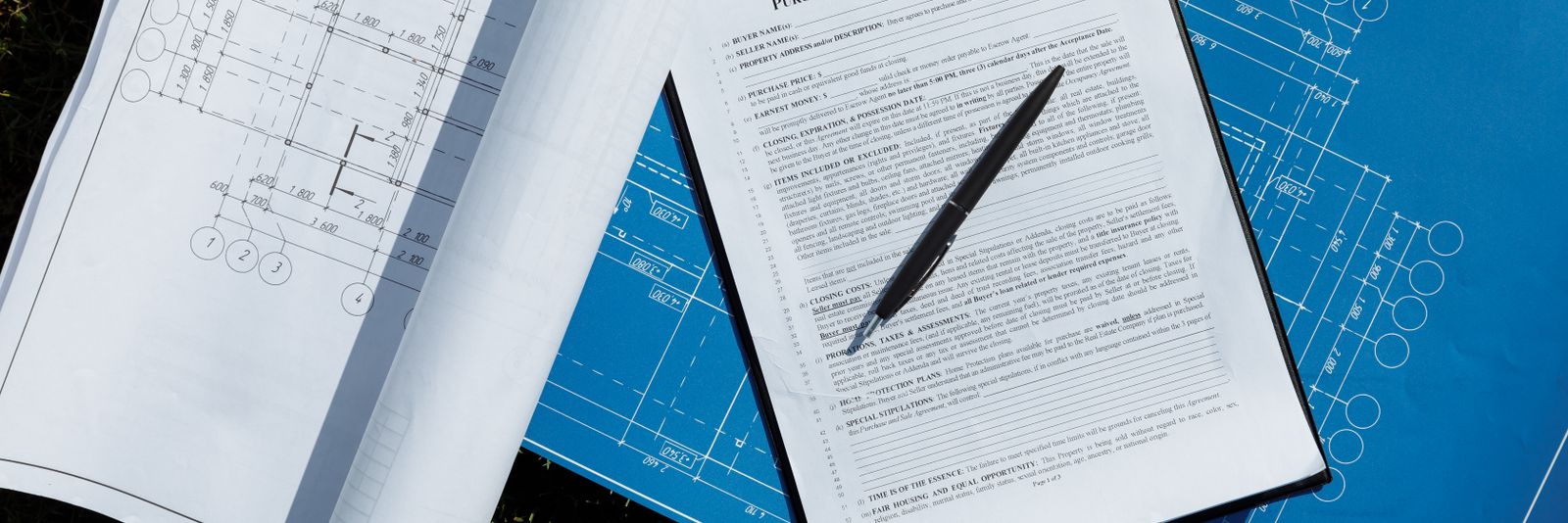 Drawings and a signed proposal laid out on a desk
