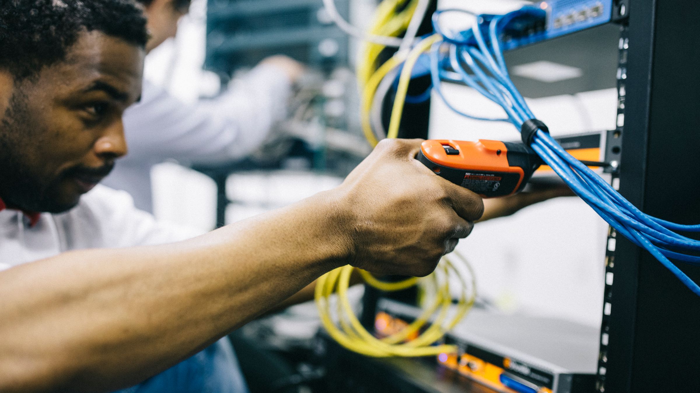 A technician terminating network cable in a communications rack