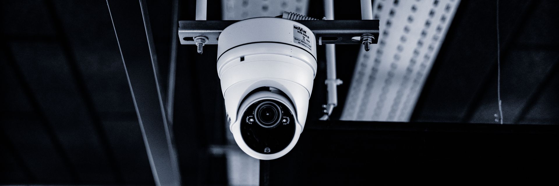 A dome surveillance camera under an industrial ceiling